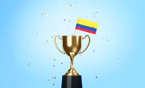 istock Championship Concept - Star Shaped Confetti Falling Onto A Gold Cup In Which Tiny Colombian Flag Sitting Before Blue Background 1313125456