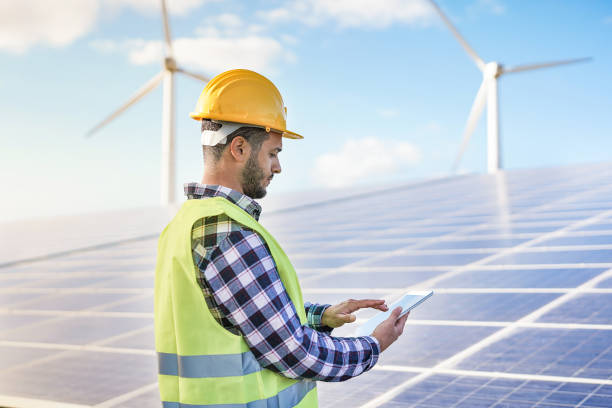 istock Man working at solar power station with digital tablet - Renewable energry with wind turbines and solar panels 1313127576
