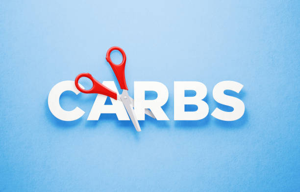 istock Cutting Carbs Concept - Scissors Cutting The Word Carbs Over Blue Background 1313127954