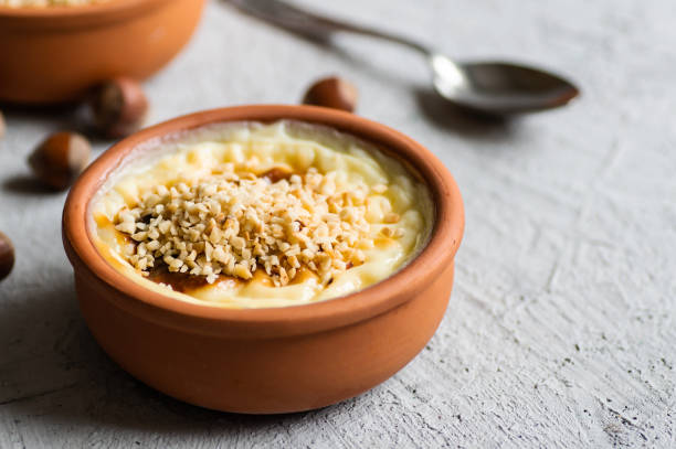 budín de arroz al horno postre lechoso turco sutlac en cazuela con palitos de canela y avellanas picadas - rice pudding fotografías e imágenes de stock