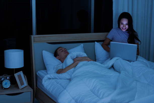 istock Woman sitting on bed in the night and using laptop computer 1313131264