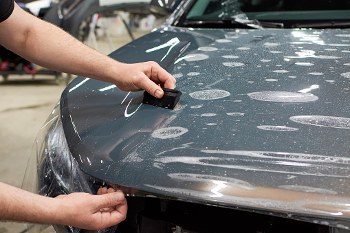 Instalación de una pintura protectora y barniz de película transparente en el coche. Película de poliuretano PPF para proteger la pintura del coche de piedras y arañazos. photo