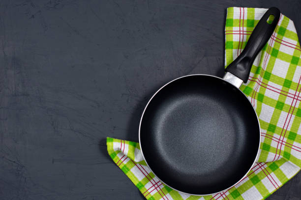 istock Empty black frying pan with kitchen towel on black table. 1313135529