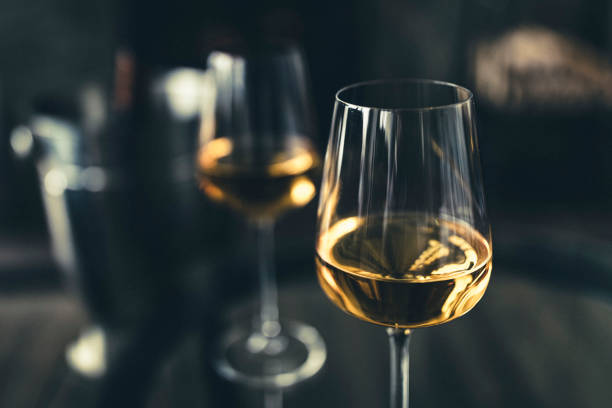 Close-up of two glasses of white wine and, in background, a bottle in an ice bucket. White wine photography. white wine stock pictures, royalty-free photos & images
