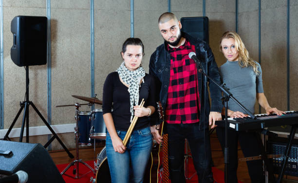 istock Three bandmates posing together with musical instruments in rehearsal room 1313136924