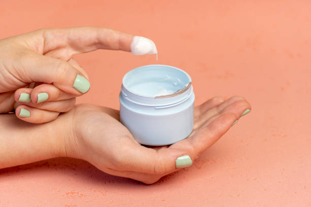 istock Female hands holding white cosmetic bottle on pink background 1313138412
