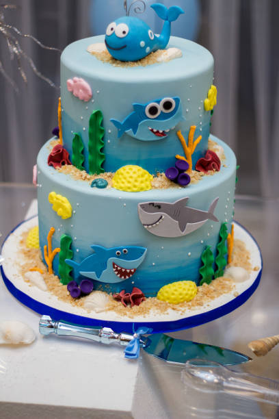 istock Fish and shark birthday cake, 2 tier cake. Knife and seashell on the table - Copy 1313141099