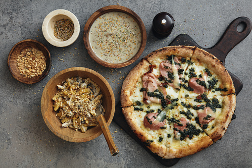 Pasta with wild mushrooms and toasted seed mix. Wild mushroom soup with bacon. Italian pizza with mortadella. Flat lay top-down composition on concrete background.