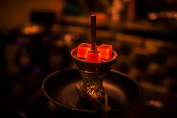 Glowing shisha coal from coconut in a shisha bar as a background