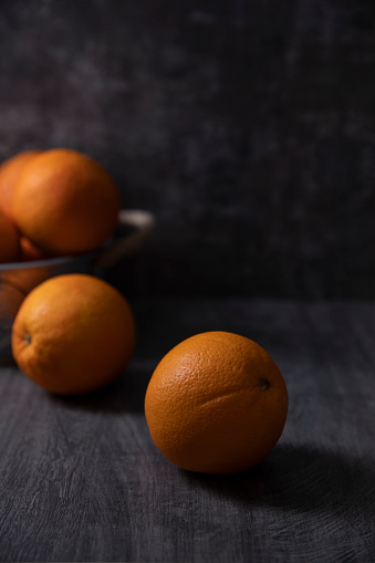 Orange fruit in a basket on dark wooden background