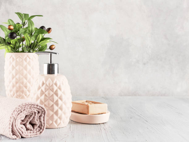 Bathroom composition. Bathroom composition. Soap dispenser, towel, natural soap and vase with olive tree on a gray background. Space for text. peach color table stock pictures, royalty-free photos & images