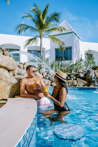 Palm Beach Aruba Caribbean, white long sandy beach with palm trees at Aruba Antilles, couple man and woman mid age on a white beach with palm trees