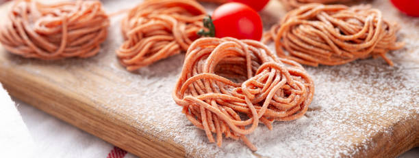 hausgemachte spaghetti mit pfeffer- und tomatengeschmack auf holzbrett auf leichtem betonhintergrund - 6729 stock-fotos und bilder