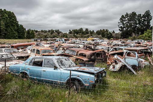 Antique cars on a big scrapyard at the end of Old Coach Road Trail, North Island of New Zealand