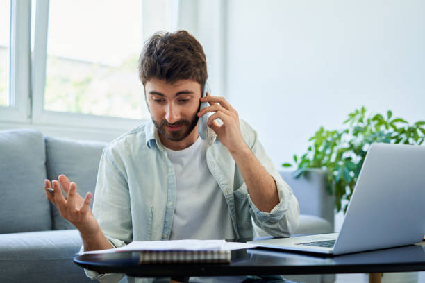 istock Unhappy man discussing bills over phone. Home finances concept. 1313158470