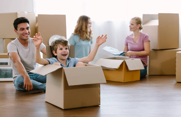 caucasian father having fun cute little son moving with cardboard boxes and teenage girl with her mother sorted out clothes and collected donations for people in need.moving to new house or apartment. - real estate imagens e fotografias de stock