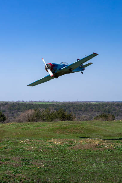 istock small single propeller plane flies low over the ground hilly landscape with green grass and blue sky on a sunny day, nobody. 1313159739