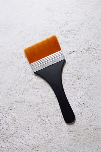 Istanbul, Turkey-April 13, 2021: A paint brush with silk bristles on a white concrete floor, A paint brush with orange bristles and a black handle. Full Frame, Still life, Flat lay. Shot with Canon EOS R5.