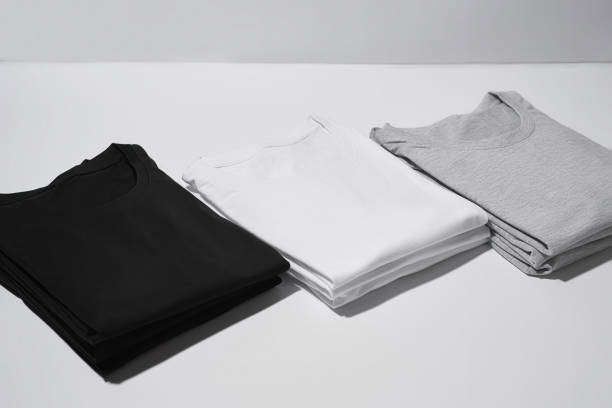 istock Three folded monochrome t shirts gray, black and white isolated over gray background 1313163932