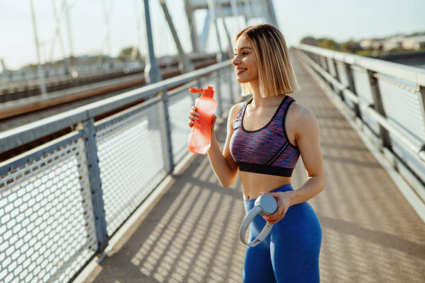 istock Young woman jogging outdoors in springtime, drinking water from plastic bottle 1313168233