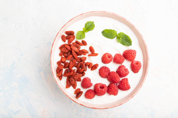 istock Yogurt with raspberry and goji berries in ceramic bowl on white concrete background. top view, flat lay, close up. 1313171377