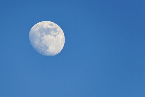 Full moon rising during spring evening with blue sky