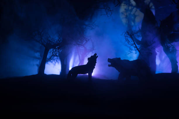 istock Silhouette of howling wolf against dead forest skyline and full moon. Creative artwork decoration. 1313172931