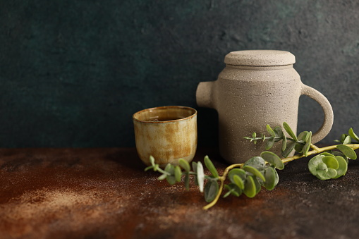 Curved ceramic cup. Mug green with handle made by hand. Pottery with glossy glaze. An empty green cup isolated on white