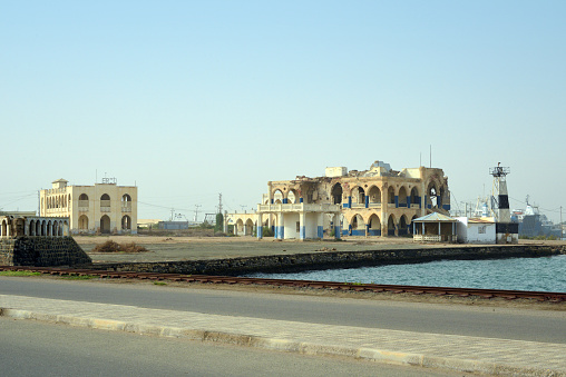 Taulud /  T'walet Island, Massawa, Northern Red Sea Region, Eritrea: Governor's Palace, Palazzo del Commissario / ERSL-Eritrean shipping lines building and harbor rear range light - the palace was built in the 19th century for Swiss adventurer Werner Munzinger, the governor appointed by the Khedivate of Egypt, on the place of the 16th century Turkish palace of Osdemir Pasha, used as Governor's palace by the Italians and as Emperor Haile Selassie's winter palace - coral block structure with bricks and reinforced concrete, survived earthquakes but not war.