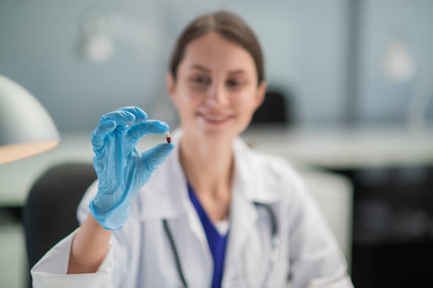 the doctor prescribes the medicine and presents the patient with its antiviral properties. a hand in a medical glove in the foreground - cheerful doctor prescribes professional occupation imagens e fotografias de stock