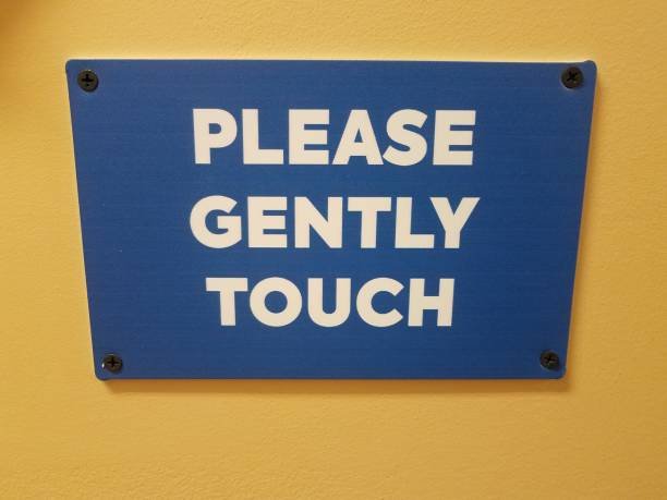 istock blue please gently touch sign on yellow wall 1313186775
