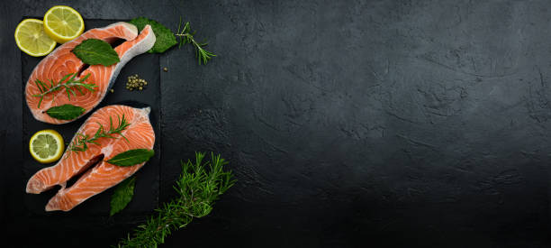 istock Fresh raw salmon steaks on a black rustic background. Seafood banner. 1313186874