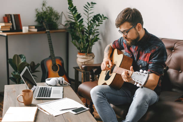 istock Young guitarist hipster at home holding guitar looking at notes 1313193942