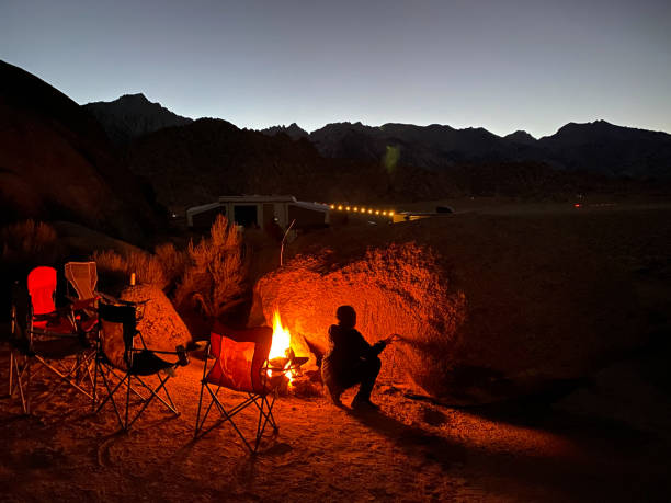 istock Child reading and playing by a campfire while camping on a road trip. 1313193999