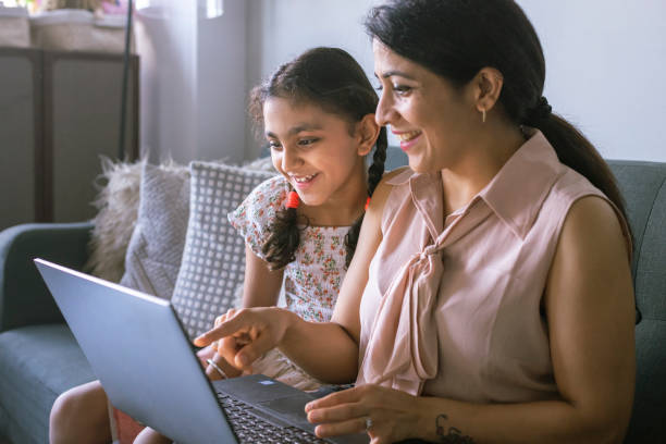 istock Mother and daughter using laptop computer at home 1313194119