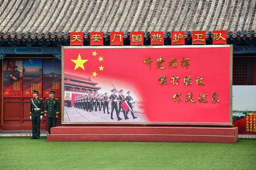 Beijing, China - November 9, 2017:  Soldiers in the Chinese Armed Forces stand by pro Chinese Communist Party sign at Tiananmen Square.