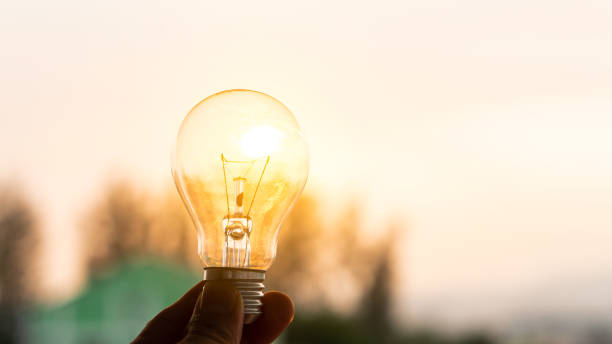 istock Solar power in nature concept light bulb hand held background with sunset evening 1313205462