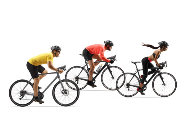 A small group of four road cyclists rides down an empty rural road with the sun at their backs for exercise and fun.