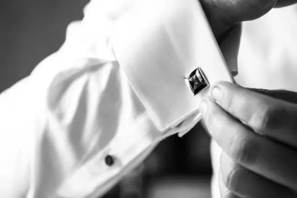 Groom putting on cufflinks as he gets dressed
