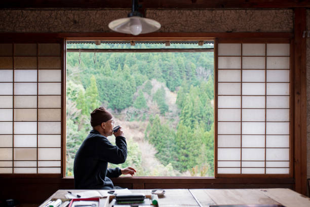 Senior Japanese artist drinking tea looking out the window