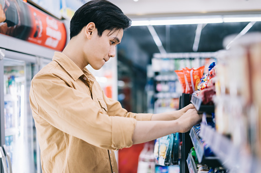 Young Asian man was wondering while shopping at the convenience store at night