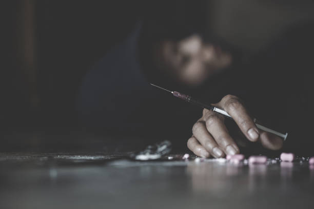 mano humana de un drogadicto y una jeringa con jeringa narcótica tendida en el suelo. día mundial contra las drogas. - imagen - narcotic drug abuse addict heroin fotografías e imágenes de stock