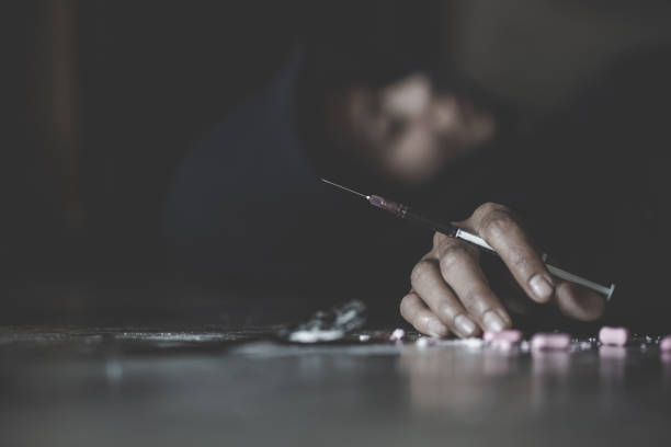 mano umana di un tossicodipendente e una siringa con siringa narcotica sdraiata sul pavimento. giornata mondiale contro la droga. - immagine - narcotic drug abuse addict heroin foto e immagini stock