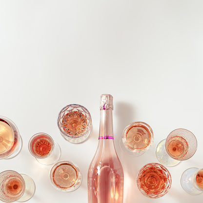 Rose wine assortment in crystal glasses, bottle of rose champagne sparkling wine on light background. Summer alcoholic drink top view, winetasting concept.