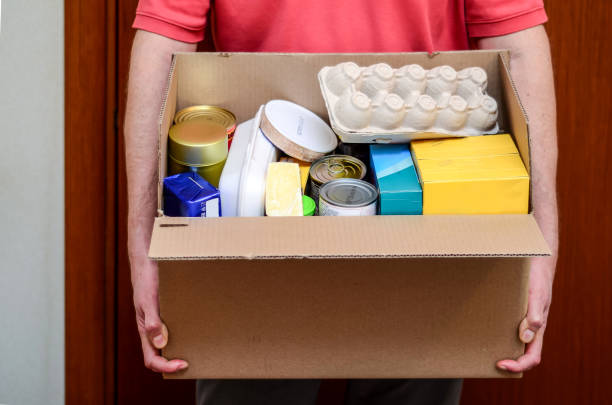 istock Delivery man with an open box full of groceries 1313216704