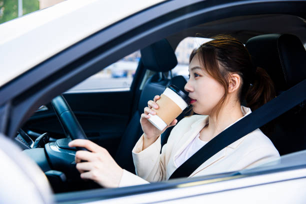 istock Young women driving a car with coffee cup in hand 1313216776