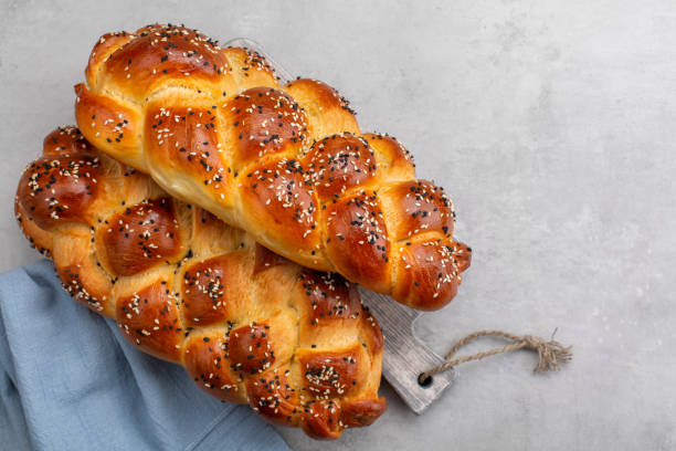 istock Homemade braided  Challah bread decorated with sesame seeds. Top view. Light grey background. Copy space. 1313216991