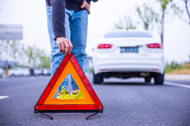 człowiek ustawia czerwony trójkąt ostrzegawczy - warning triangle triangle car warning sign zdjęcia i obrazy z banku zdjęć