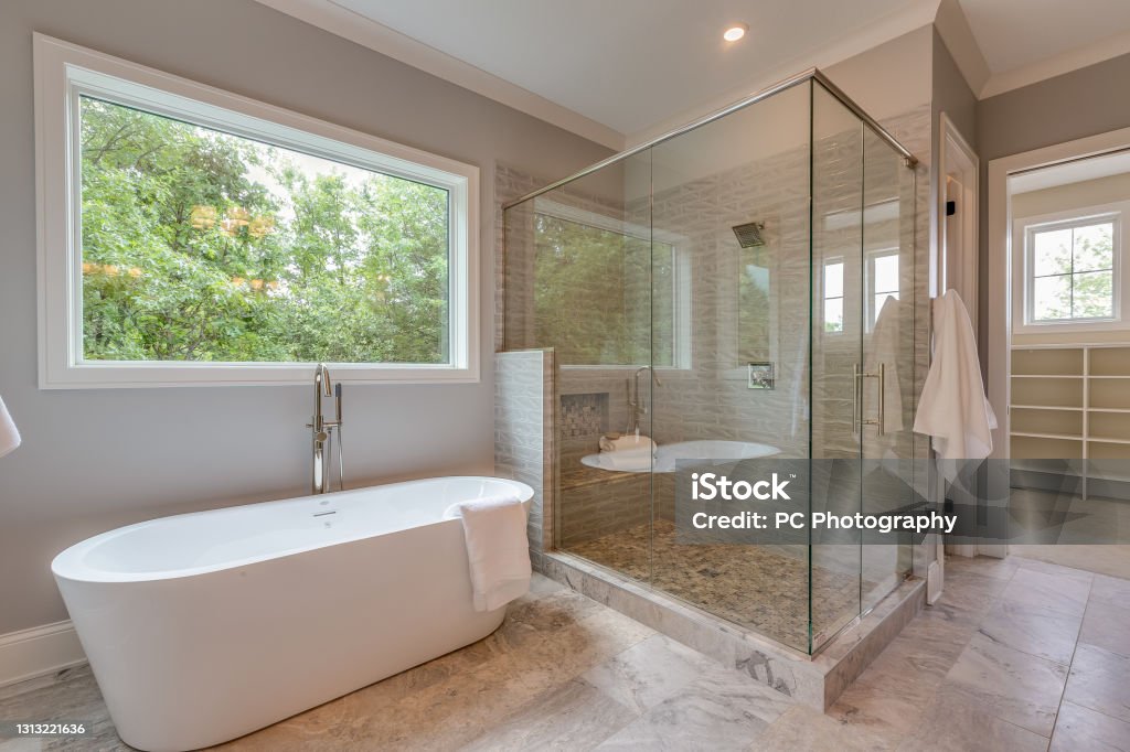 Large glass shower and free standing bathtub Huge window for natural light in spacious bathroom Bathroom Stock Photo