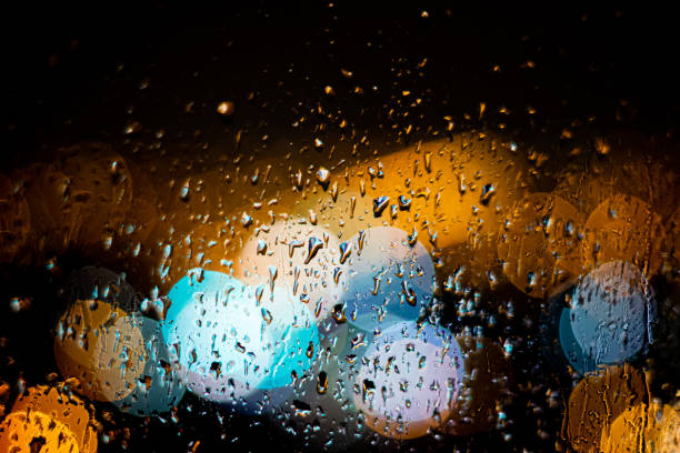 istock Drops of rain on window blured citylights at night 1313222833